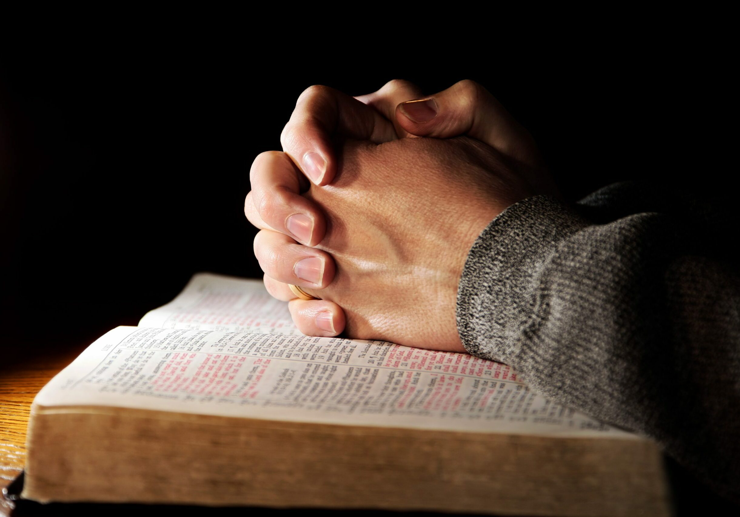 Hands of a man praying in solitude with his Bible (Christian image shallow focus).